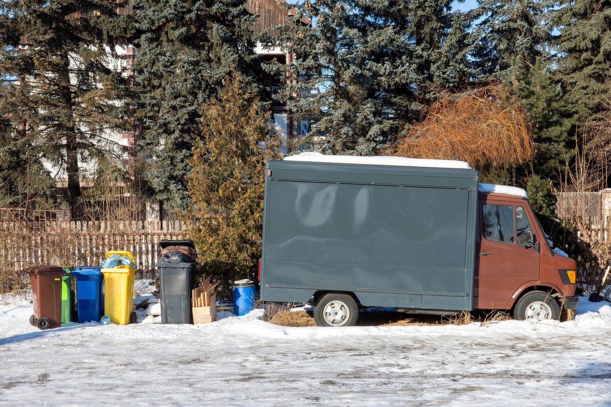 Commercial bins staged for pickup near a service vehicle